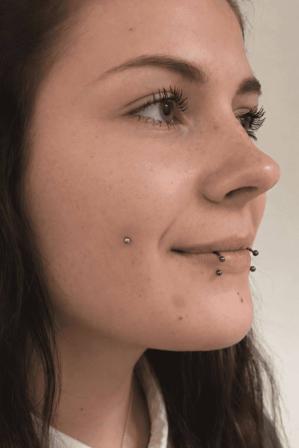 femme souriante portant un dolphin bites et un microdermal à la joue